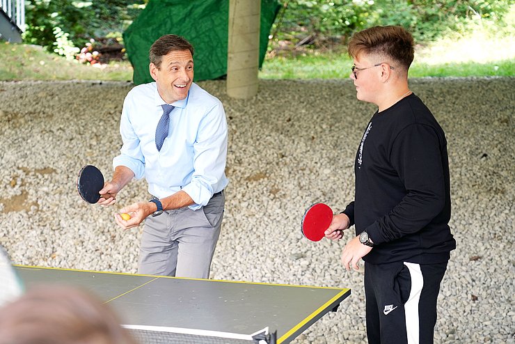 Ein Mann spielt mit Kindern Tischtennis.