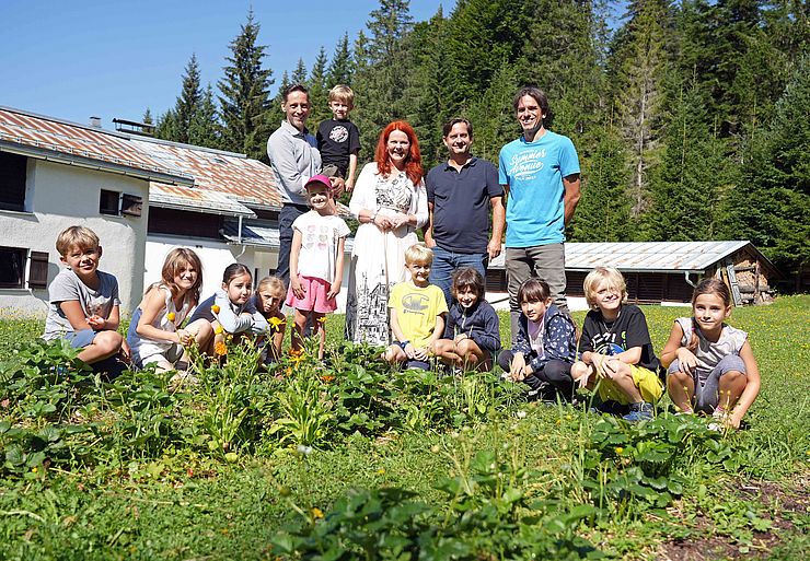 Clemens Mair, LRin Cornelia Hagele, Michael Steinlechner und Christian Biendl zusammen mit einer Gruppe Kindern auf einer Wiese.