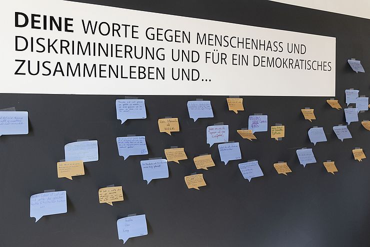 Auf einer schwarzen Tafel sind viele orange und blaue Post-its angebracht.