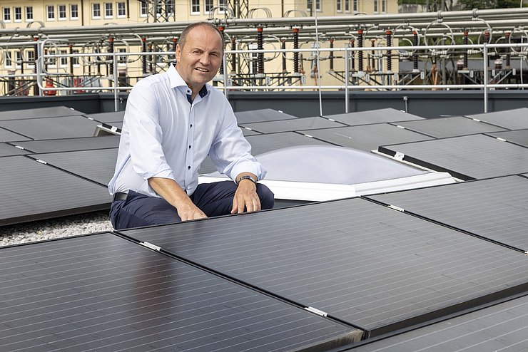 Mann hockt zwischen PV-Modulen