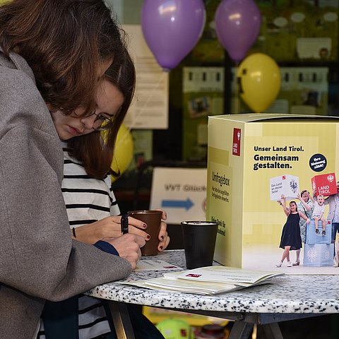 Zwei Kinder, die Umfrage ausfüllen neben Umfragebox