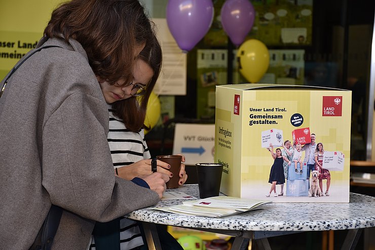 Zwei Kinder, die Umfrage ausfüllen neben Umfragebox