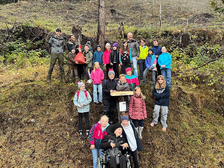 Kinder und zwei Erwachsene auf Gruppenfoto in einem Wald 