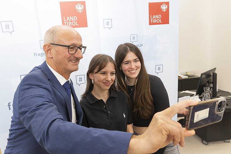 Der Landeshauptmann macht ein Selfie mit zwei Schülerinnen. 