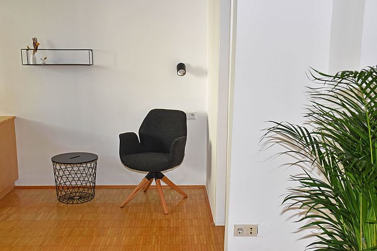 Raum mit Holzboden, Stuhl, Tisch und Pflanze