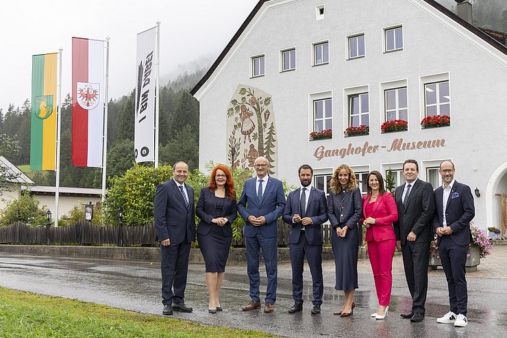 Alle Mitglieder der Tiroler Landesregierung nebeneinander vor einem weißen Haus.