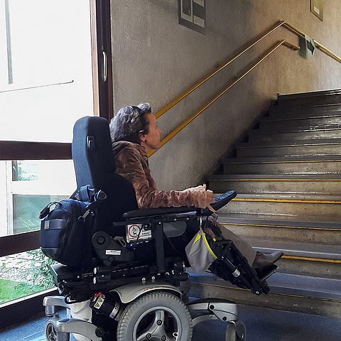 Eine Frau im Rollstuhl vor einer Treppe