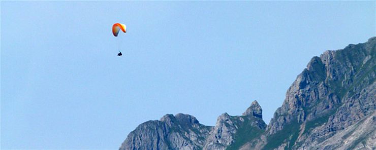 Paragleiter fliegt über Bergspitzen