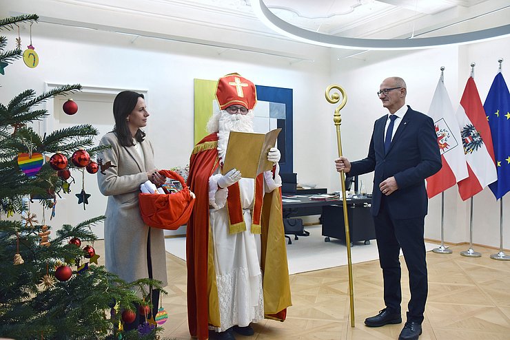 Der Nikolaus liest den beiden aus seinem goldenen Buch vor.