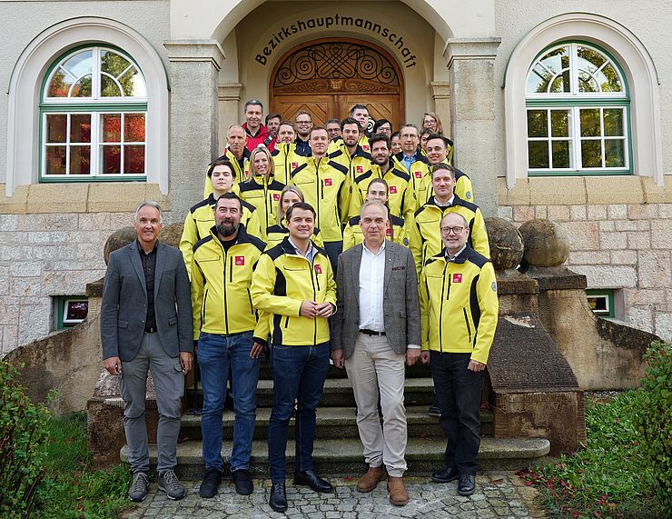 Gruppenfoto vor der BH; fast alle tragen gelbe Einsatzjacken