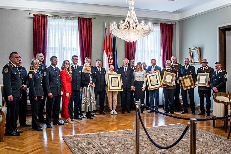 Ein großes Gruppenfoto mit vielen Menschen; einige von ihnen tragen Feuerwehruniformen