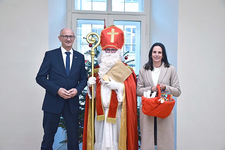 LH Anton Mattle, der Nikolaus und GFin von "Bruder und Schwester in Not" Marika Eisner zusammen vor einem Christbaum.