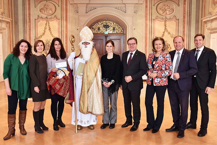 Die Regierungsmitglieder stehen zusammen mit dem Nikolaus im Parissaal im Landhaus.