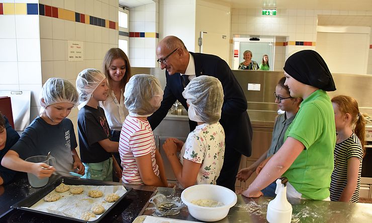 LH Mattle begrüßt Schülerinnen in einer Küche in der sie gerade Brot backen.