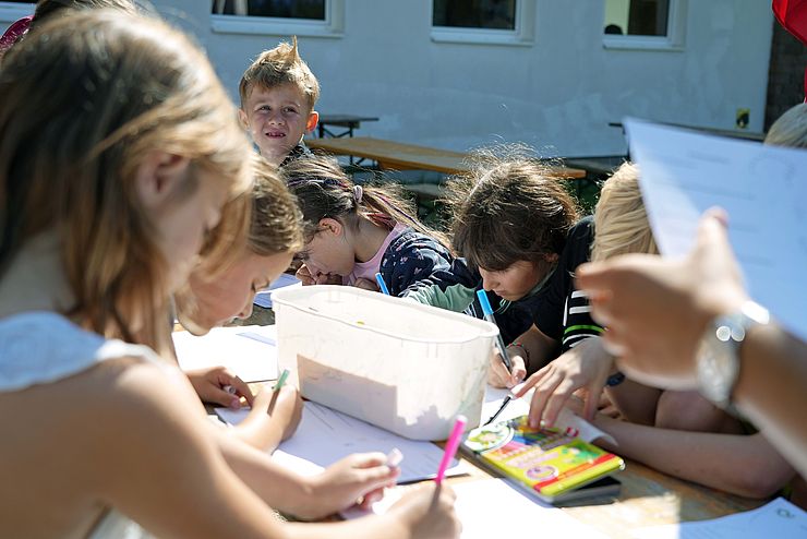 Die Kinder bemalen Blätter mit Farbe.