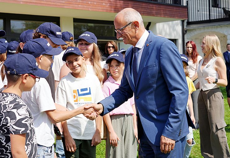 Ein weiteres Bild, auf dem der Landeshauptmann Kindern die Hände reicht. 