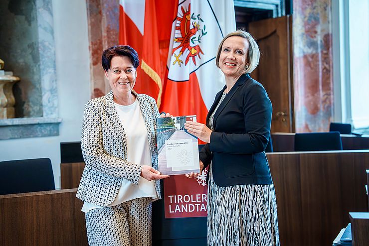 Landesvolksanwältin Doris Winkler-Hofer (re.) übergibt Landtagspräsidentin Sonja Ledl-Rossmann den Jahresbericht.
