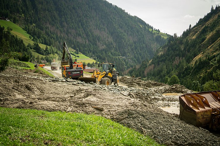 Bagger stehen auf Straße und räumen Mure weg