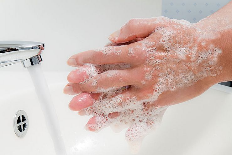 Frau wäscht sich mit fließendem Wasser und Seife die Hände