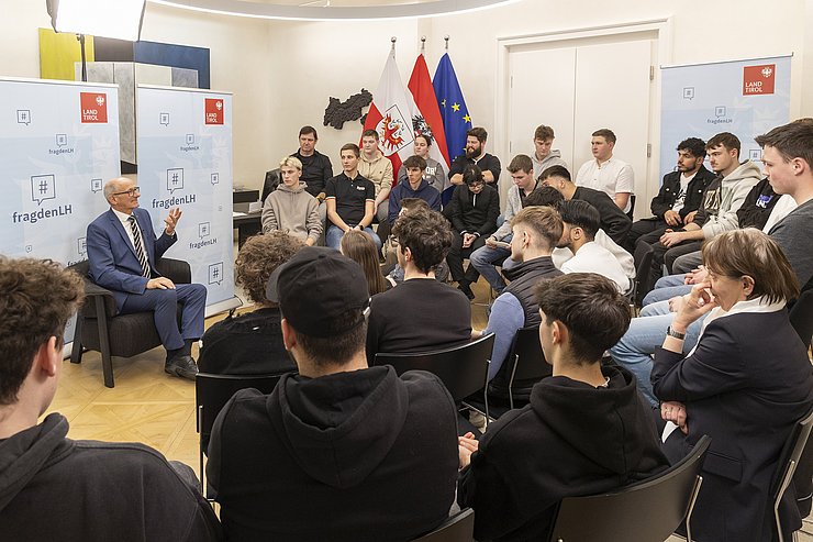 © Land Tirol/Die Fotografen Viele Menschen sitzen in einem Raum und sprechen miteinander.