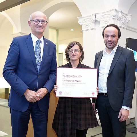 Landeshauptmann Anton Mattle und Landesrat Philipp Achammer (Südtirol)überreichten den Paul-Flora-Preis 2024 an Linda Jasmin Mayer.