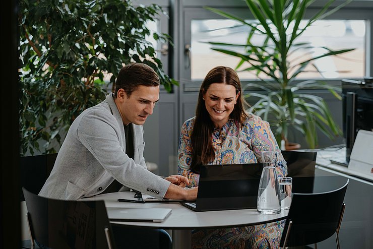 © Land Tirol/Charly Schwarz Mann und Frau sitzen am Tisch und arbeiten an Laptop