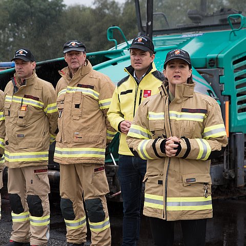 Mair in Feuerwehrjacke neben Feuerwehrmännern stehend