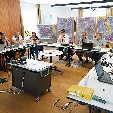 Bezirkseinsatzleitung sitzt um Tische mit Laptops, im Hintegrund Karten