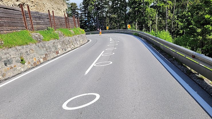 Kurve auf Landstraße mit weißen Ellipsen auf dem Asphalt