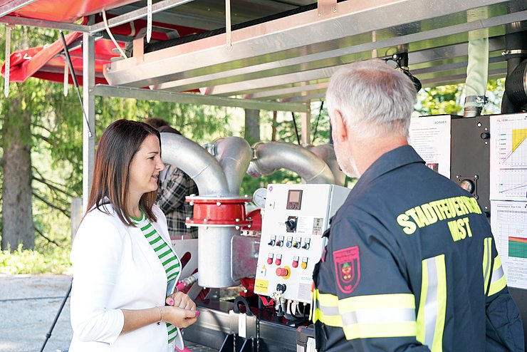 LRin Mair mit Feuerwehrmann vor Grußpumpe redend