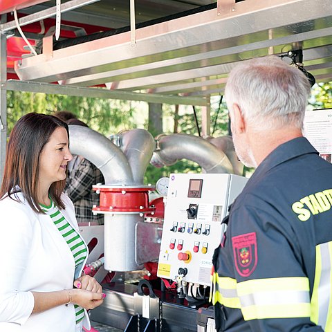 LRin Mair mit Feuerwehrmann vor Grußpumpe redend